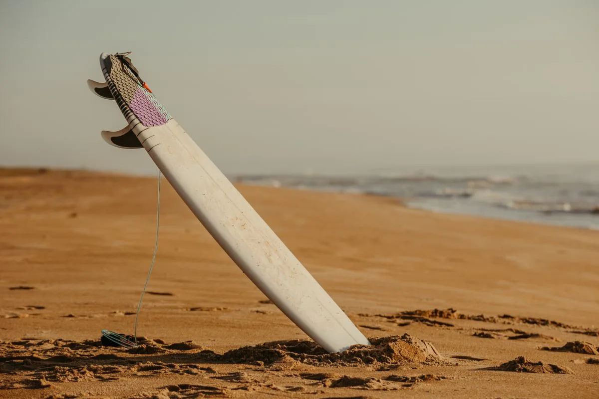 Surfboard planted upright in beach sand