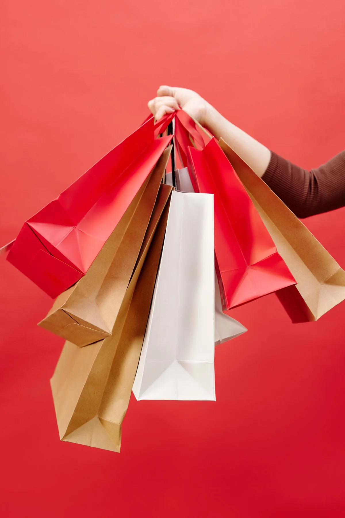 Hand holding a bundle of paper shopping bags